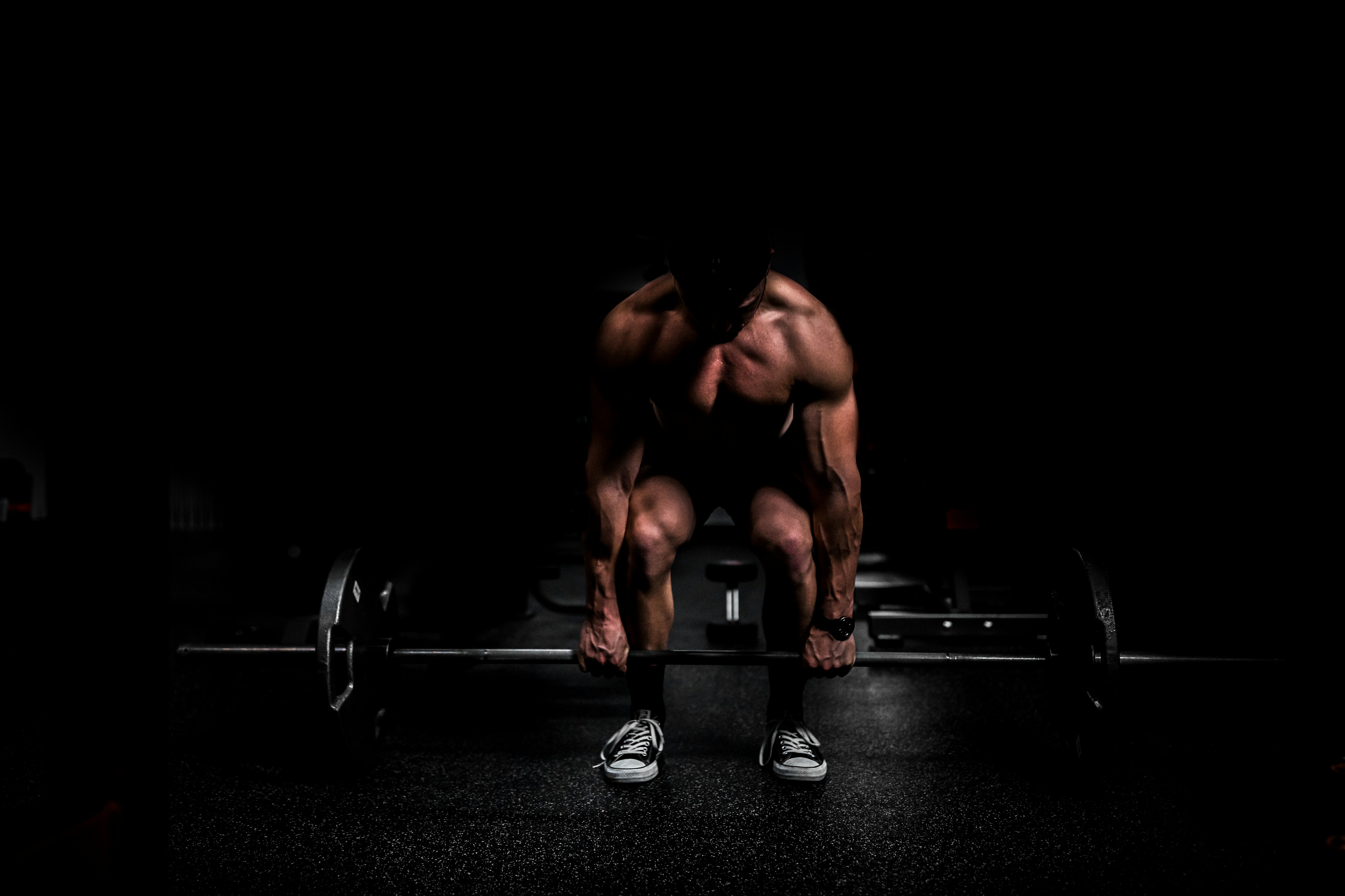 A training session underway: deadlift under a single hard light in a near-black studio